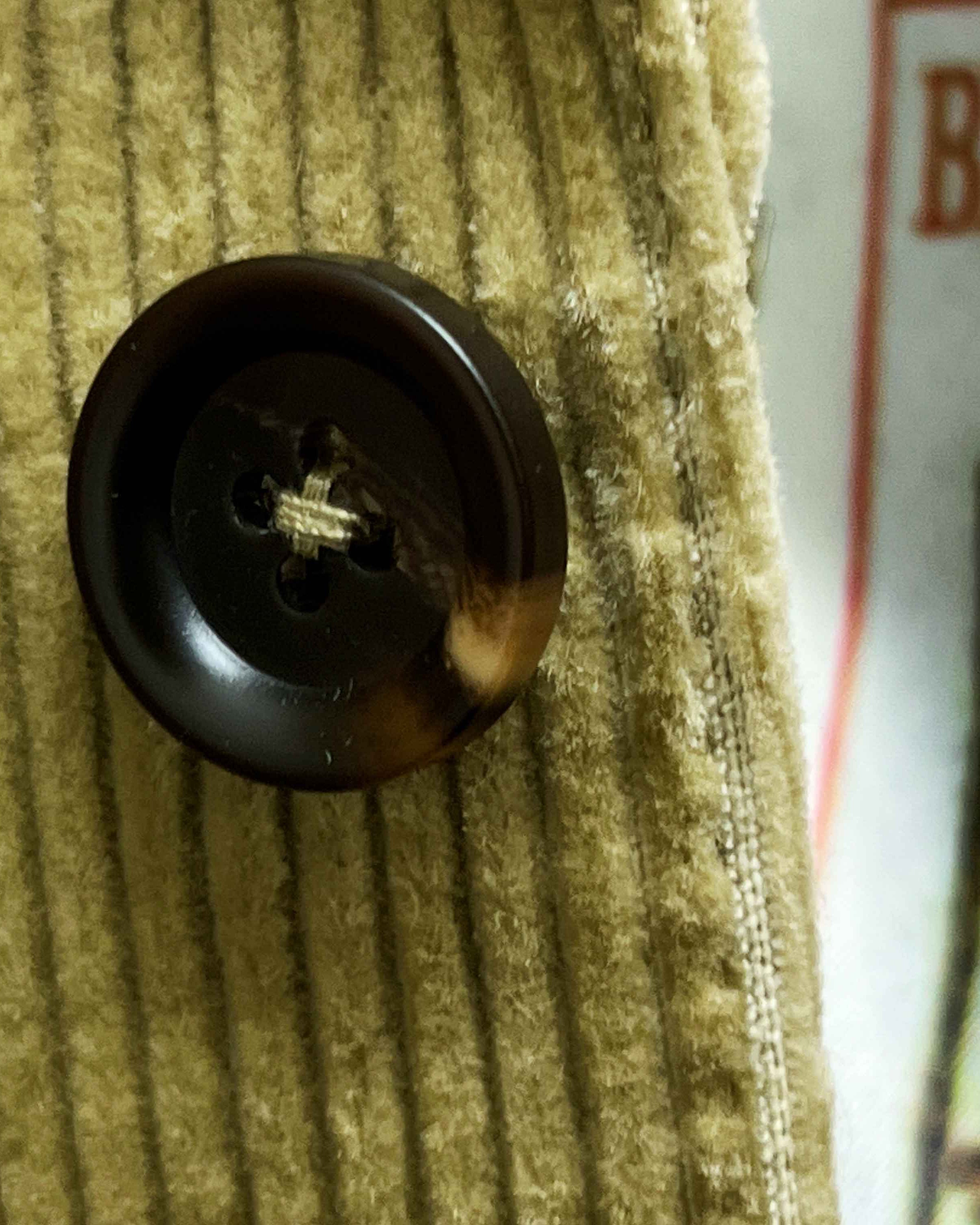 Close-up of chocolate brown horn buttons on tan corduroy sport coat showing natural marble-like patterns