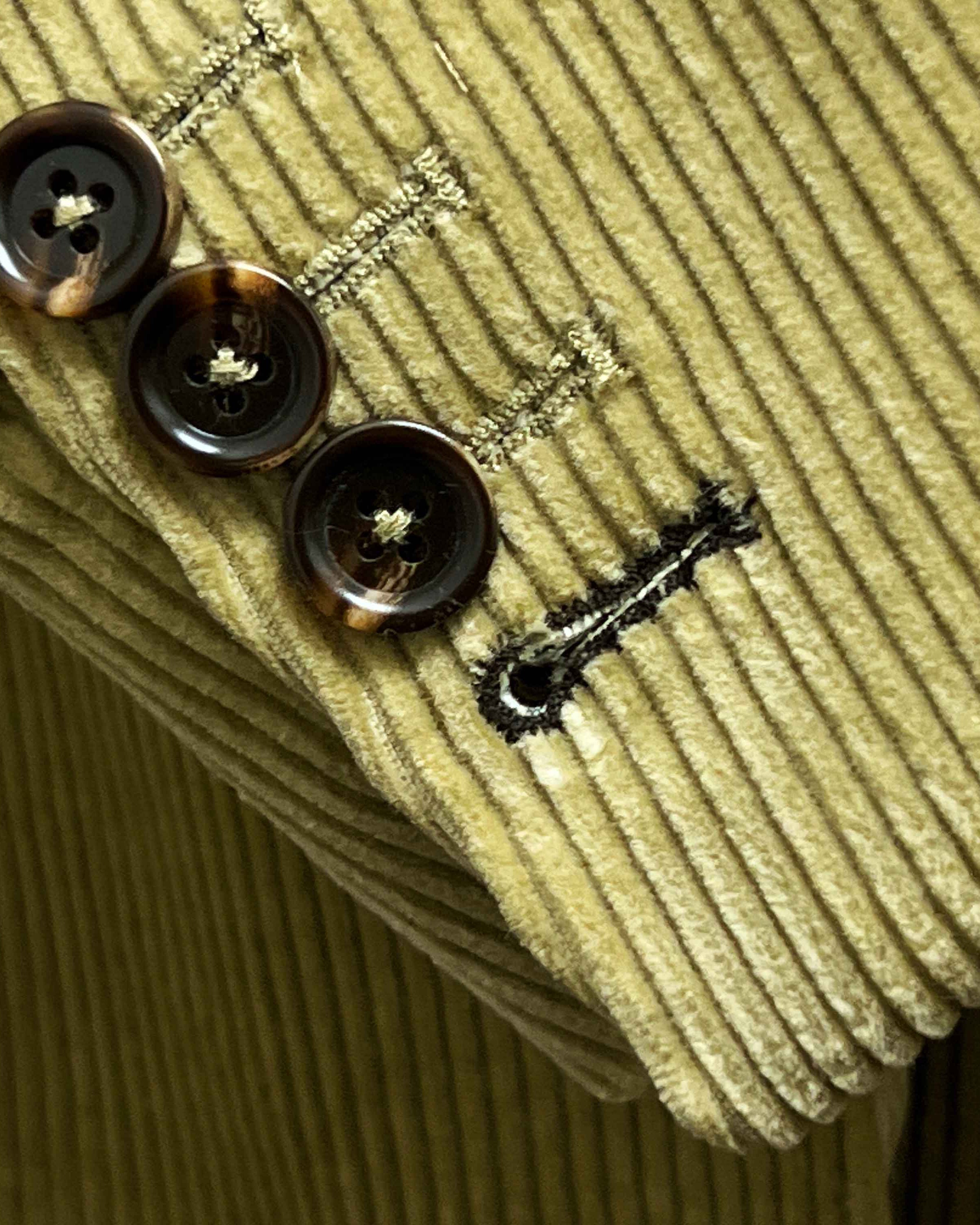 Sport coat sleeve cuff showing functional buttonholes with contrast dark brown accent stitching on tan corduroy fabric