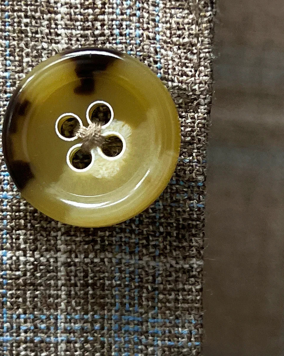 Close-up of tan and deep brown horn buttons on tan blue windowpane sport coat showing natural marble-like patterns