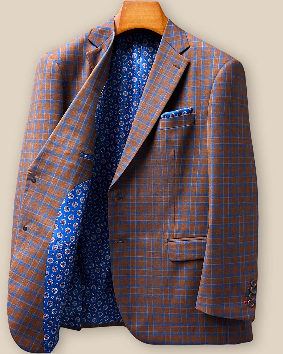 Detailed view of brown horn buttons against tobacco brown and cobalt blue check fabric showing natural texture and premium button selection