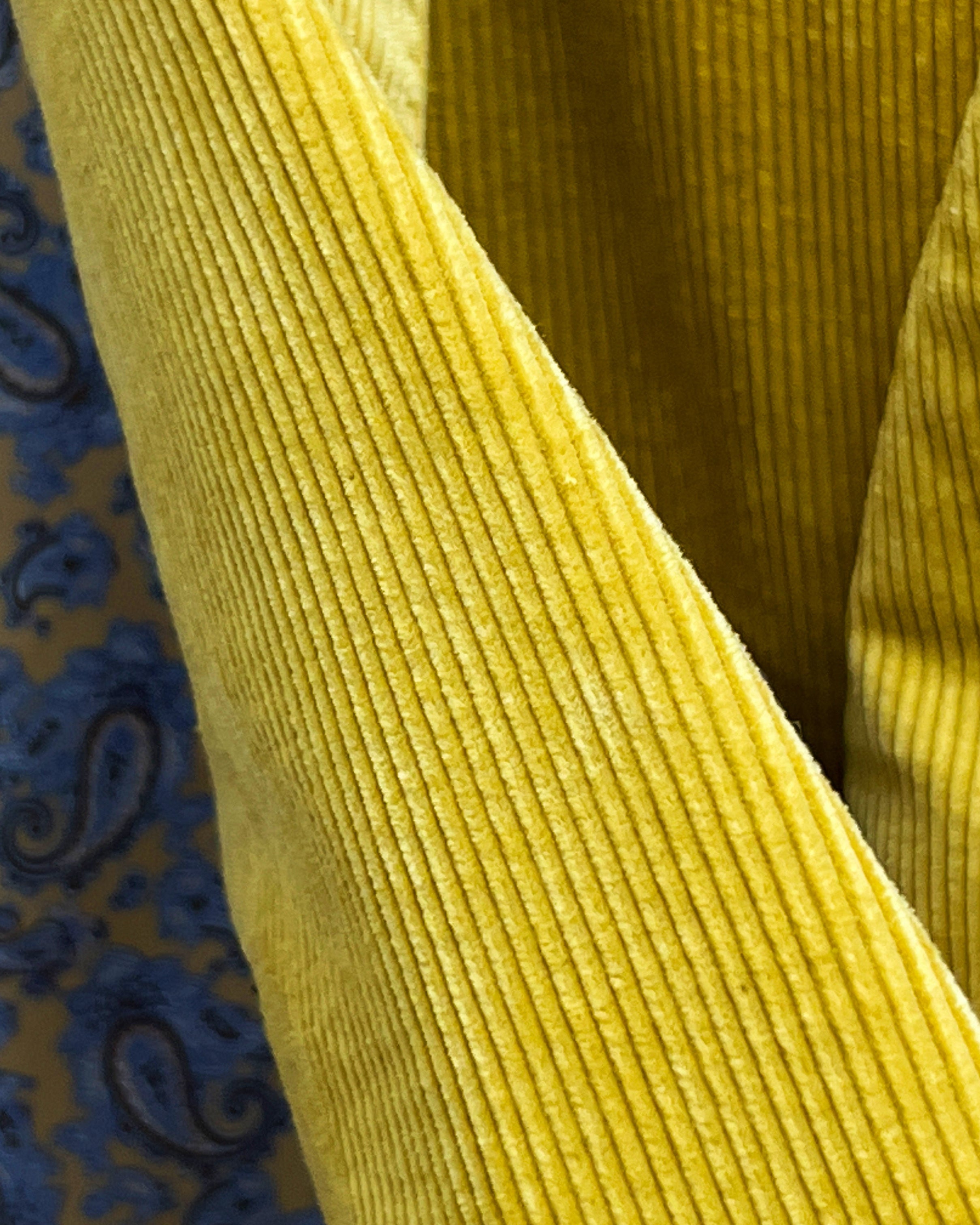 Macro view of 10 wale corduroy texture on warm mustard yellow sport coat showing distinctive ridge pattern