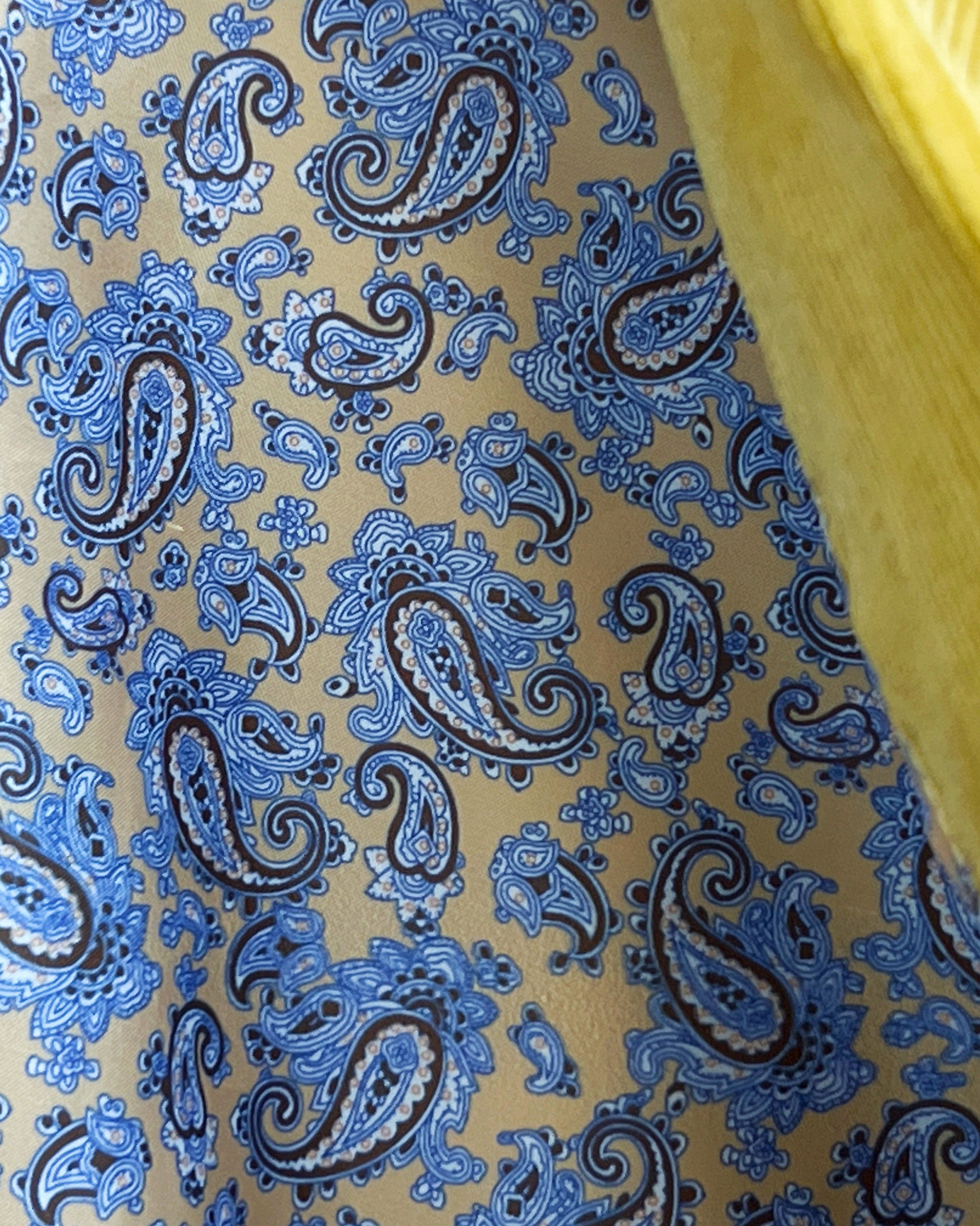 Colorful flash lining detail visible at jacket cuffs and vents in beige silk with blue paisley pattern