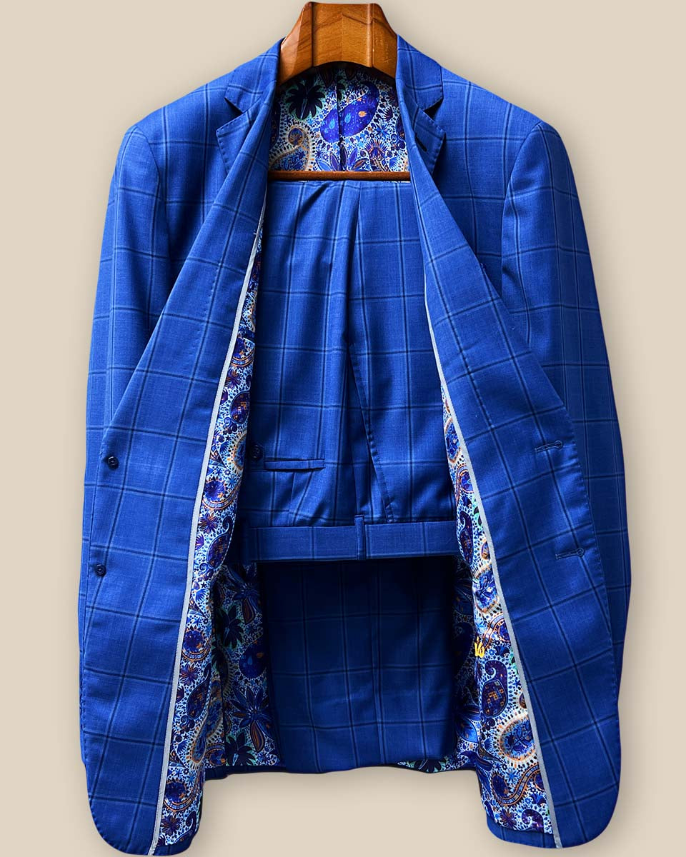 Complete two-piece royal blue windowpane custom suit displayed on hanger showing jacket and trousers with navy check pattern