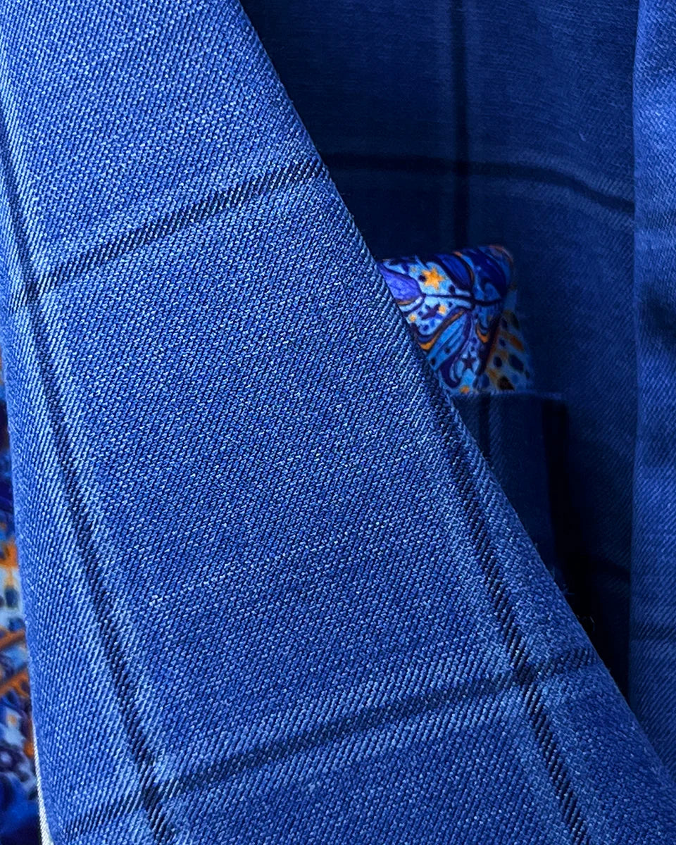 Contrast dark blue accent buttonholes on royal blue windowpane suit jacket sleeve showing precise hand-finished stitching