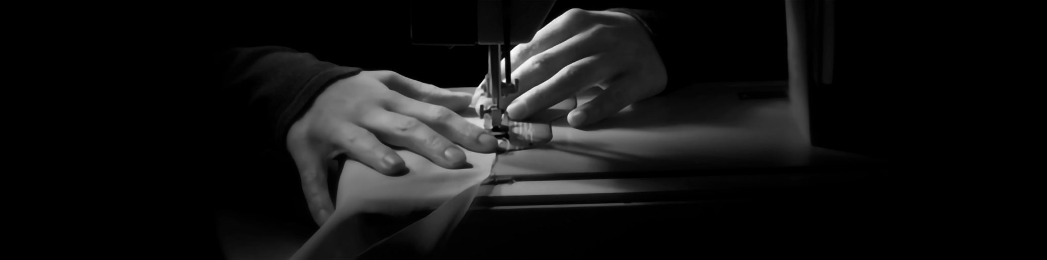Hand Holding Down Fabric Under A Needle Stitching Machine Sewing A Custom Tailored Suit