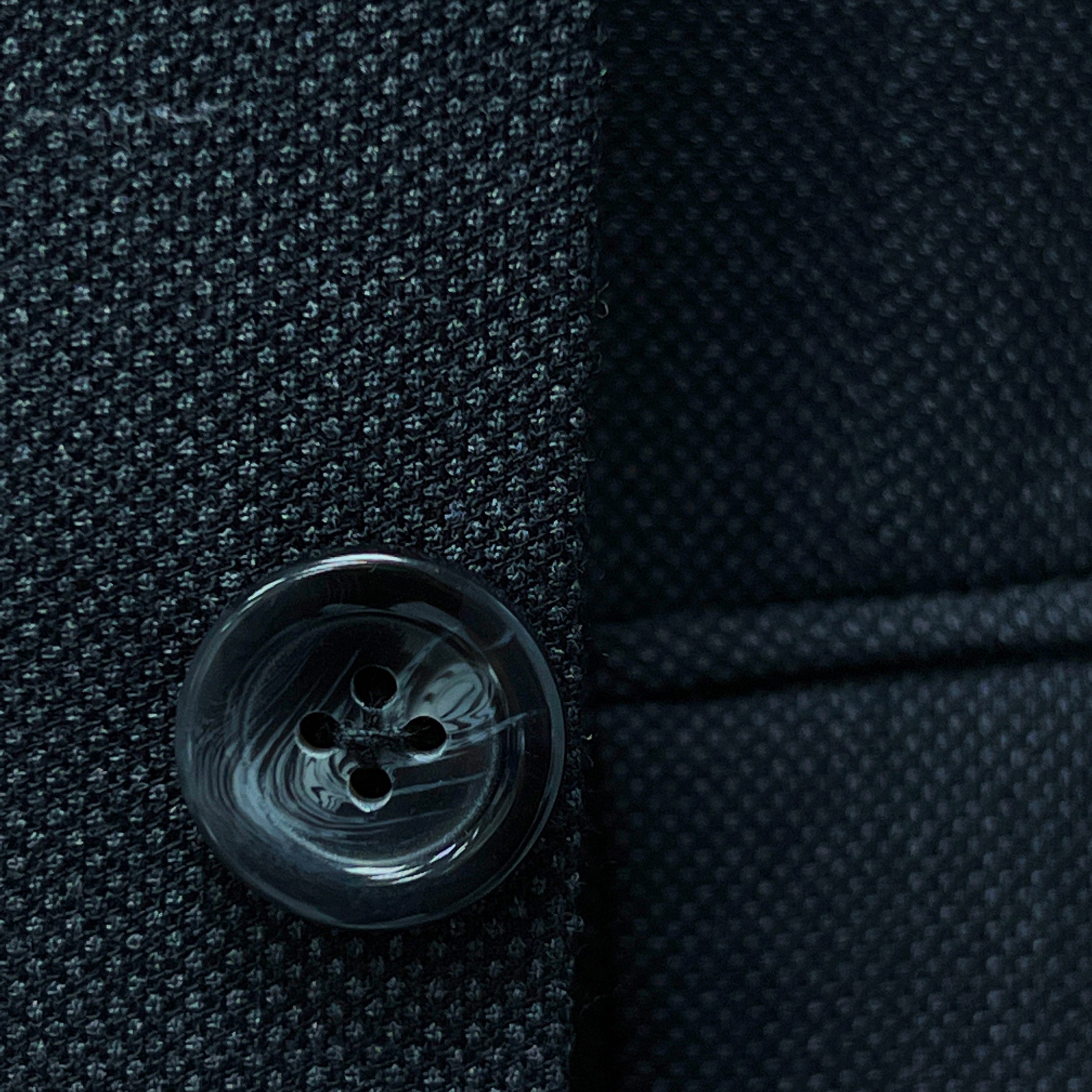 Dark grey birdseye custom suit, detailed view of the lapel and button, ideal for online design