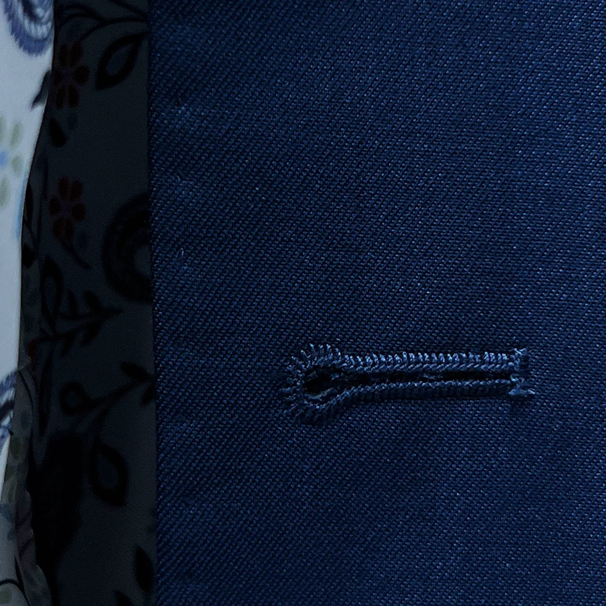 Macro shot of white contrast buttonhole stitching on royal navy blue sharkskin fabric