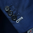 Detailed view of suit jacket sleeve, showing functional buttonholes with white contrast stitching