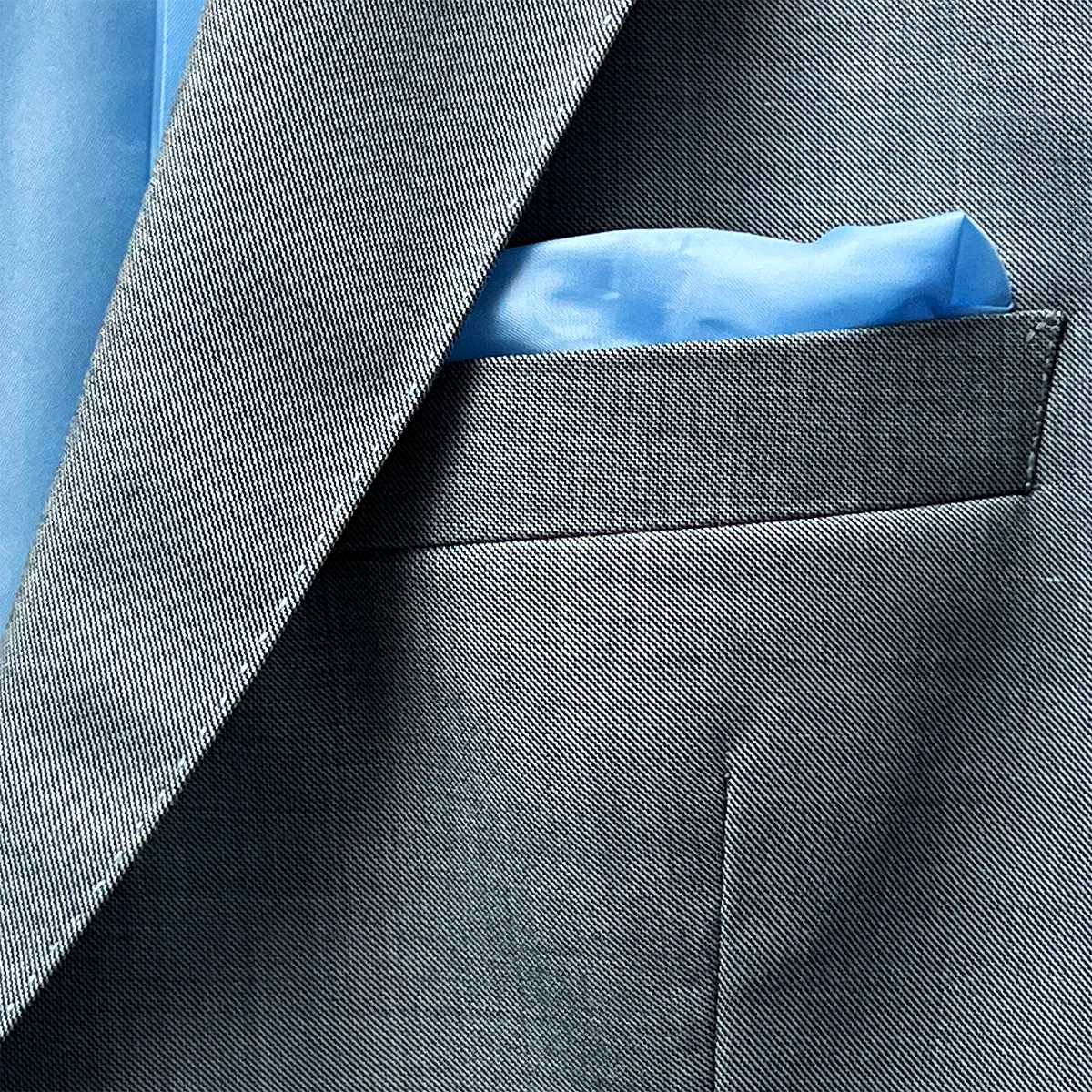 Built-in pocket square on the light grey suit, neatly tucked into the straight flap pocket.