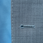 Detailed view of the sky blue hand-sewn pick stitching on the light grey suit jacket.