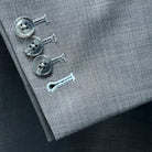 Functional sleeve buttonholes on the light grey suit with sky blue accent stitching on the buttons.