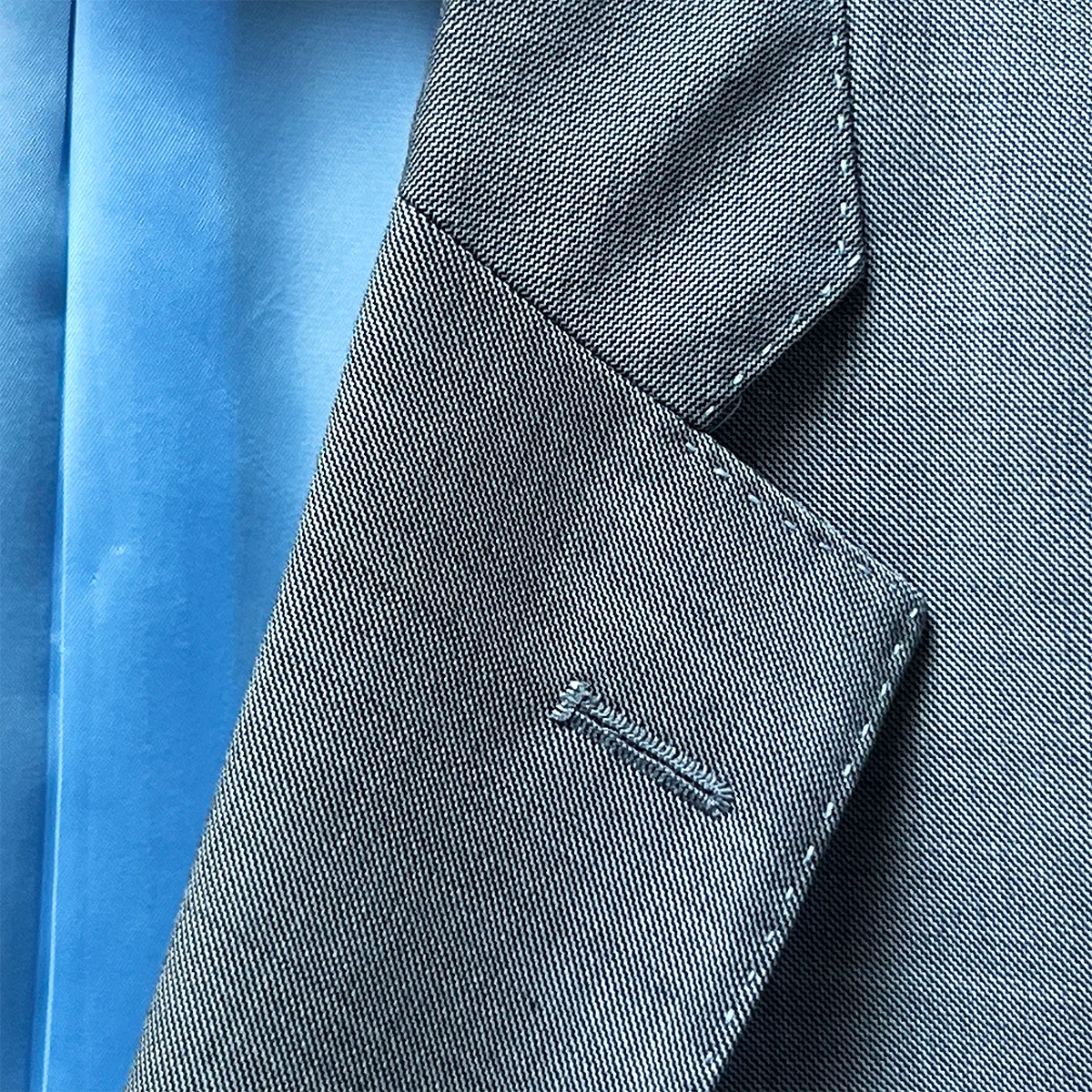 Notch lapel detail on the light grey sharkskin suit with sky blue accent buttonhole stitching.