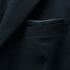 View of the built-in pocket square in the jacket's pocket, complementing the black herringbone fabric.