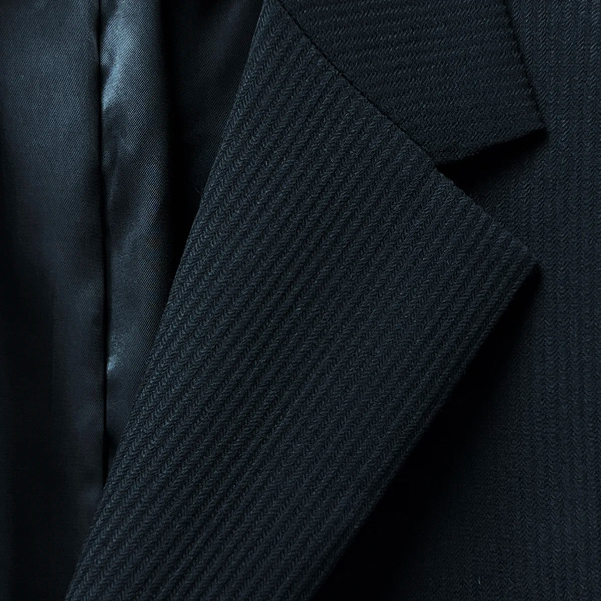 Close-up of the notch lapel, showcasing the black herringbone design and tailored finish.