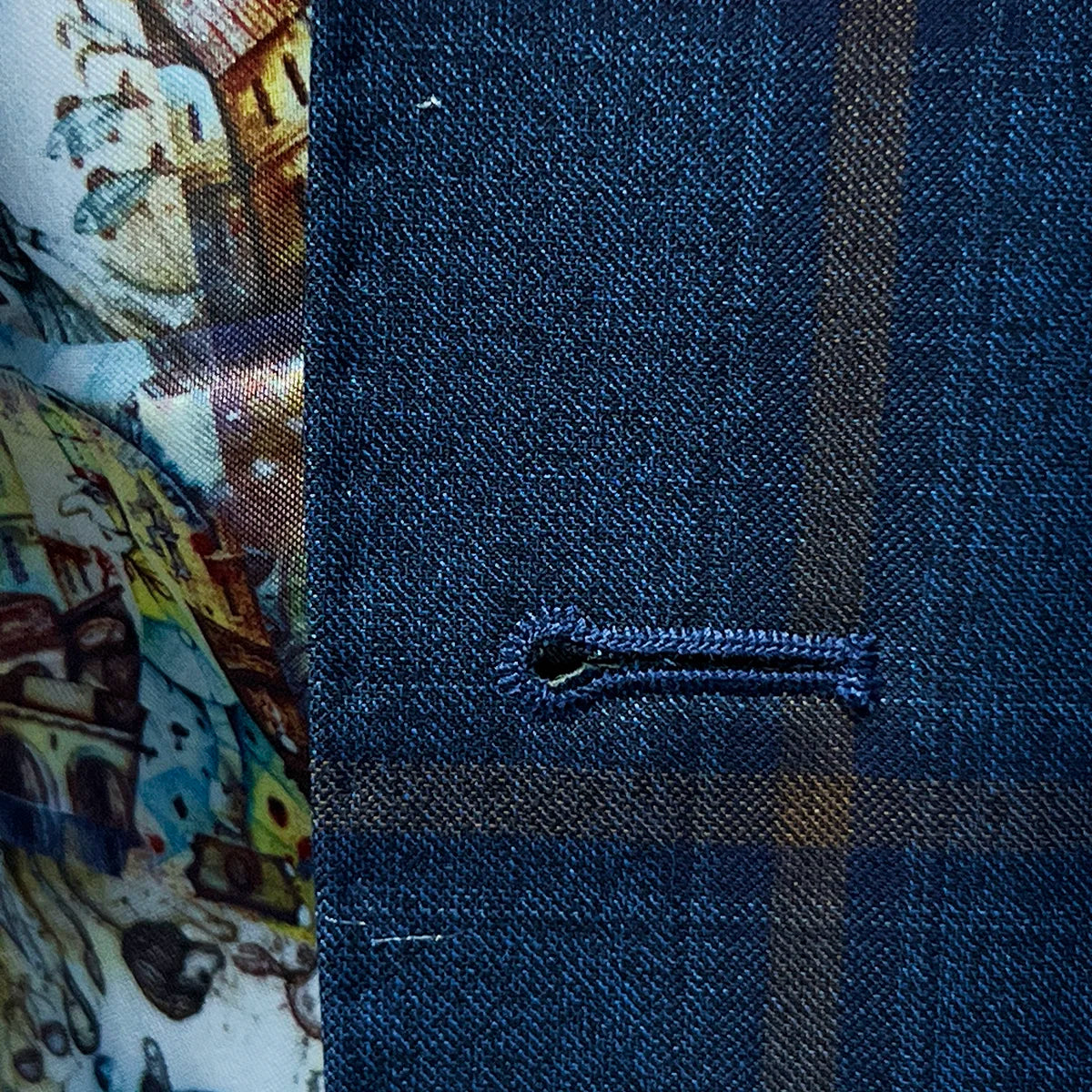 Detailed view of the buttonhole stitching, highlighting the brown accent color on the blue with bronze windowpane fabric.