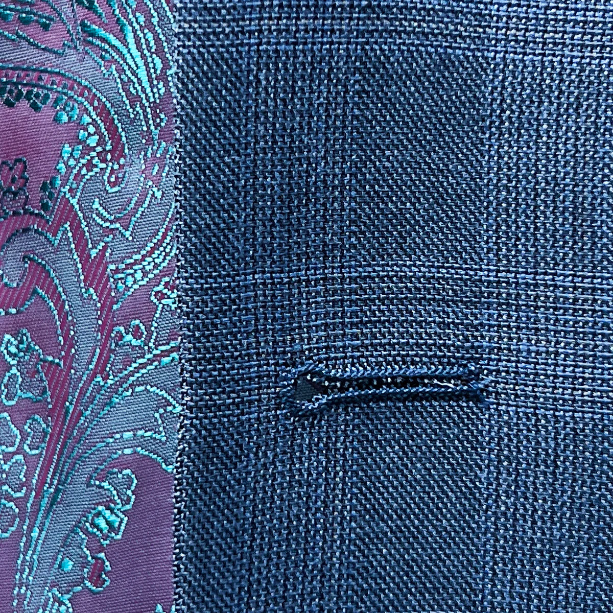 Detail of the buttonhole stitching on the suit jacket, highlighting the craftsmanship and quality.