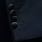 Detail of the functional sleeve buttonholes, showcasing the black satin-covered buttons and precise stitching.
