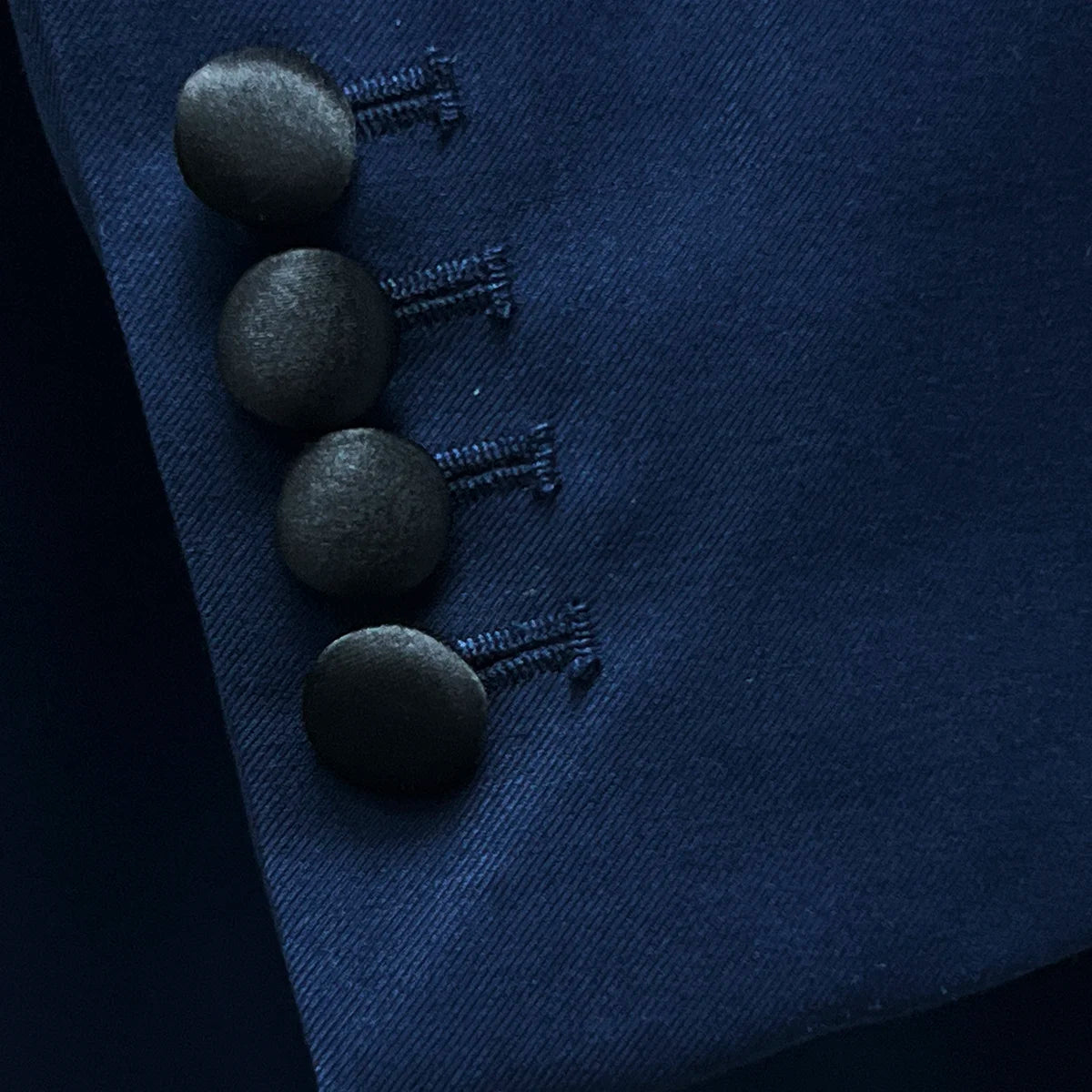 Close-up of the functional sleeve buttonholes, featuring the black silk satin-covered buttons and careful tailoring.