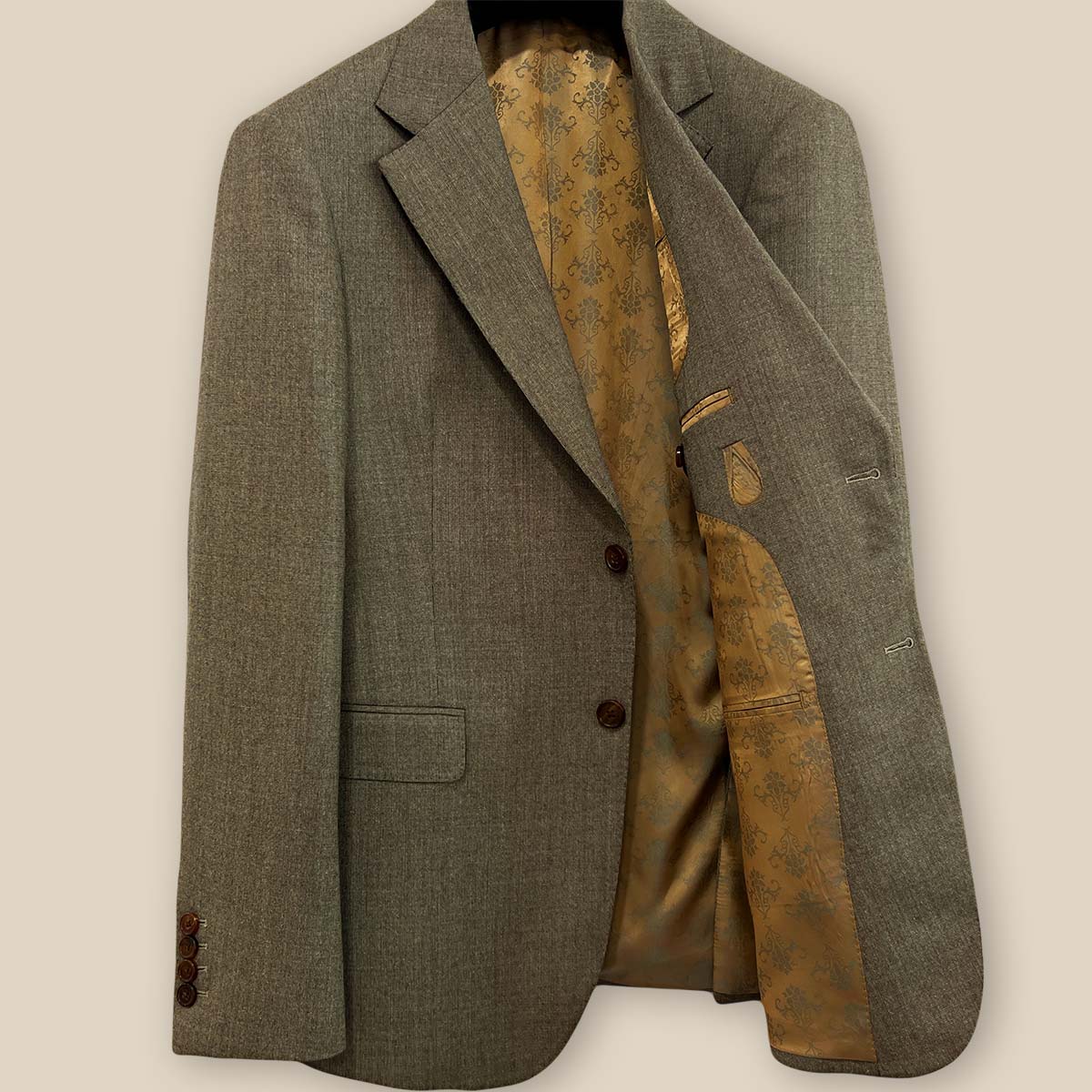 Inside view of the left side of the Westwood Hart brown nailhead men's suit jacket, revealing the gold patterned lining and interior pockets.