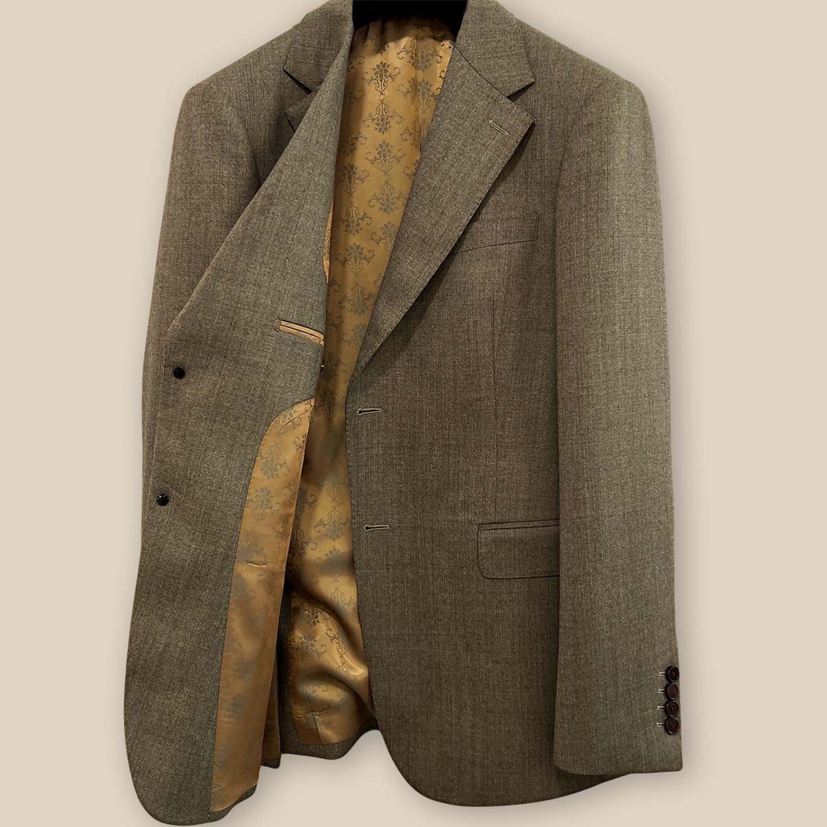 Inside view of the right side of the Westwood Hart brown nailhead men's suit jacket, featuring the gold patterned lining and pocket details.