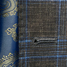 Close-up of the buttonhole stitching showcasing the hand pick stitching on the chocolate brown with blue windowpane plaid fabric.