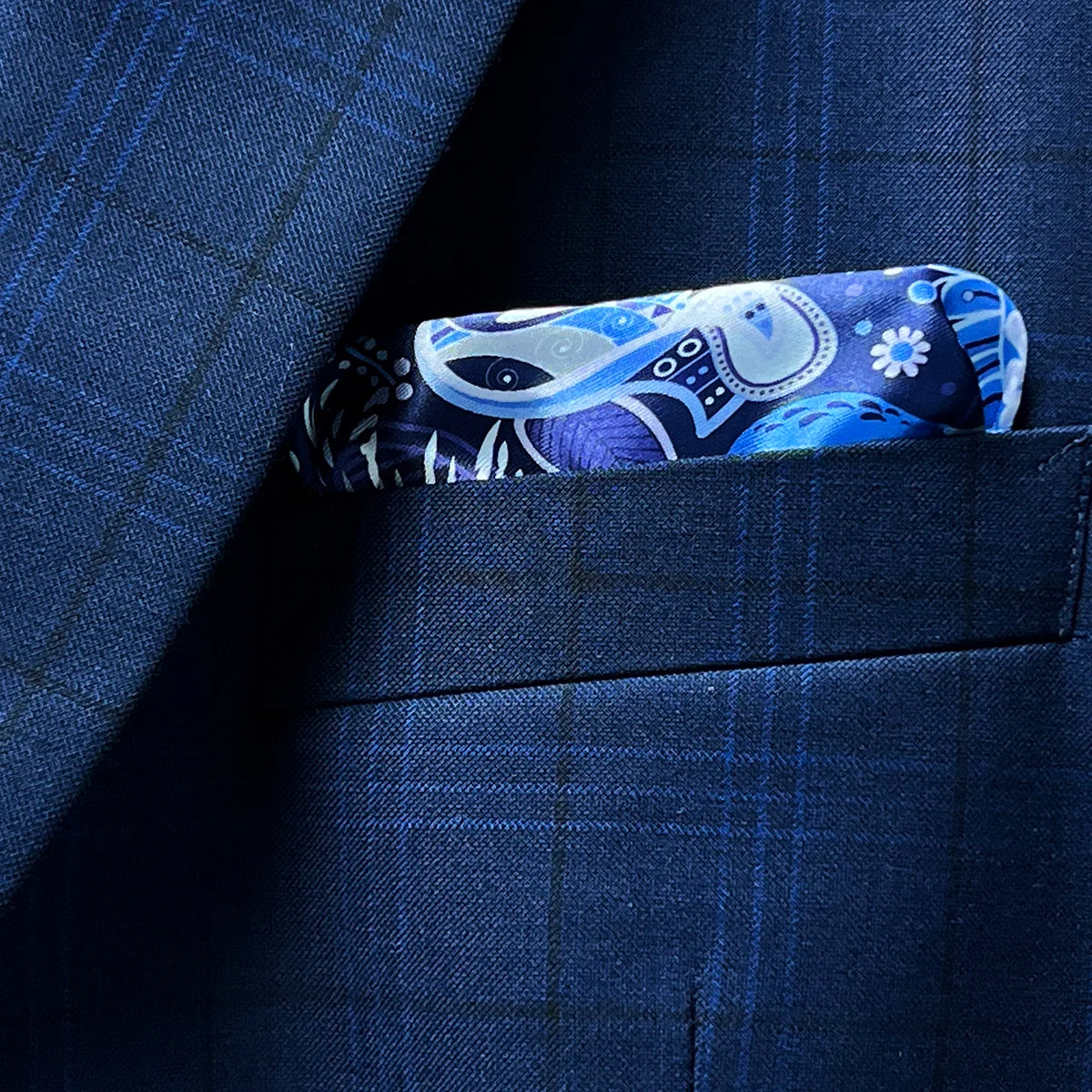 View of the built-in pocket square on the dark blue windowpane men's sport coat with a hint of the blue and white aviary motif lining.