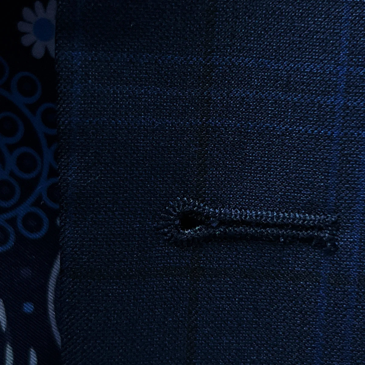 Detailed view of the buttonhole stitching on the dark blue windowpane men's sport coat featuring royal blue accent stitching.