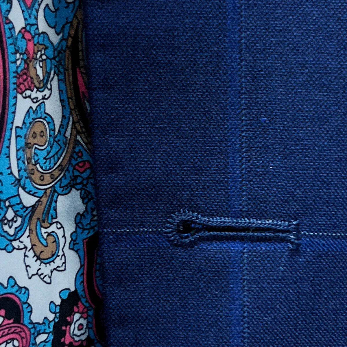 Detailed image of the hand pick stitching on the buttonholes, showcasing the white contrast thread on the royal blue fabric.