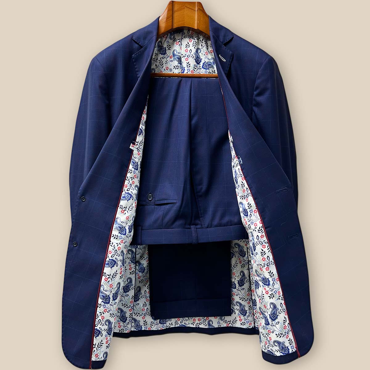 Front view of complete two-piece navy suit with subtle red windowpane pattern, showcasing the notch lapels and overall silhouette