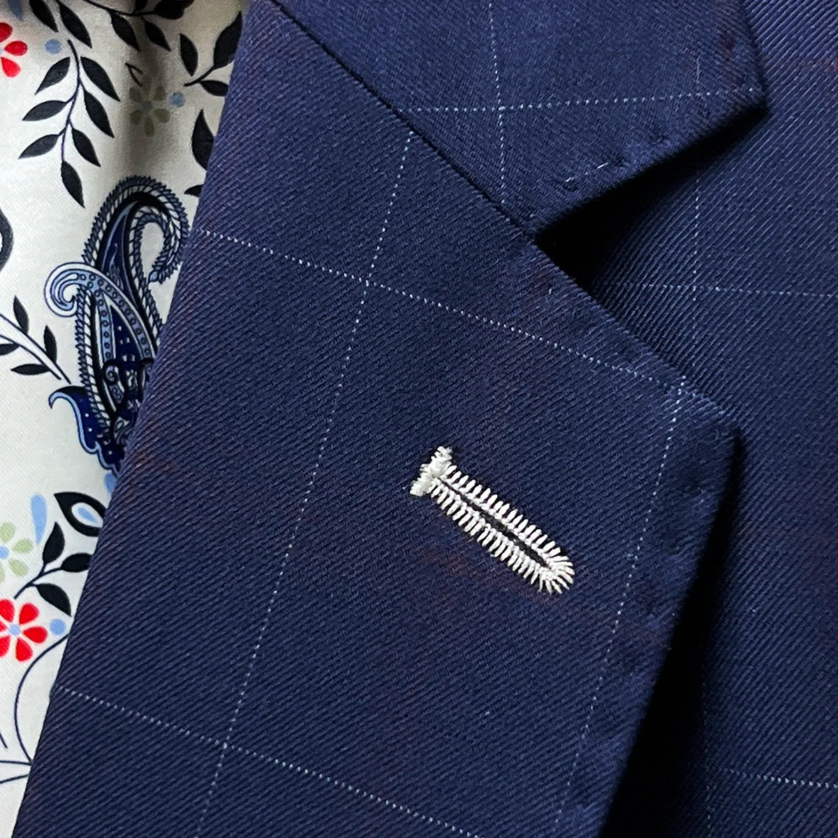 Detail of the classic notch lapel construction on the navy windowpane suit, showing the angle and proportion of the lapel