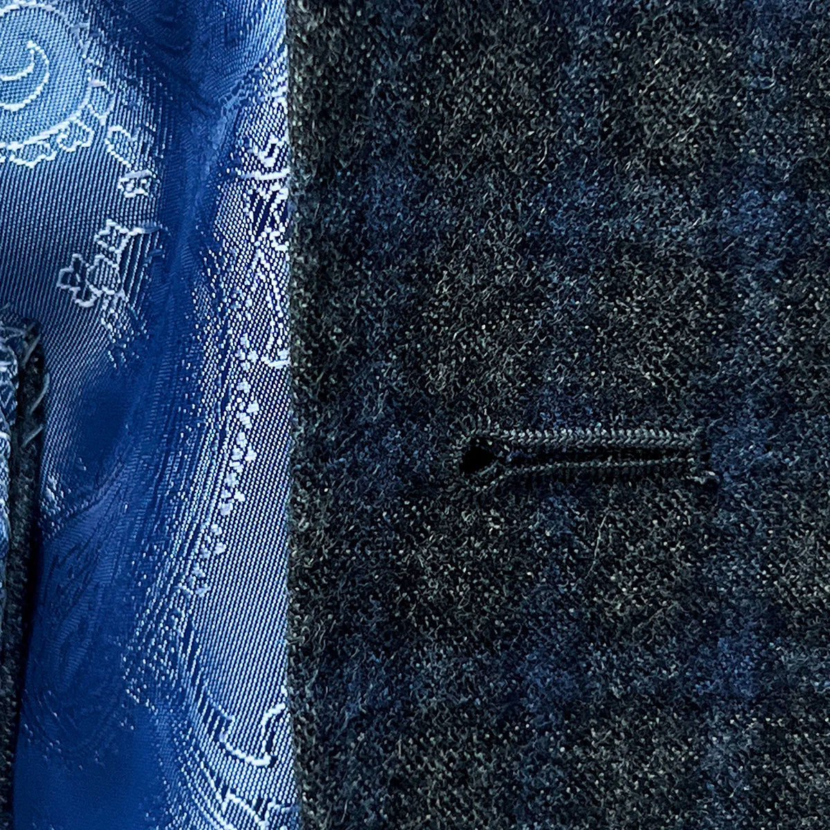 Close-up of a buttonhole on a grey blue grid check flannel sportcoat.