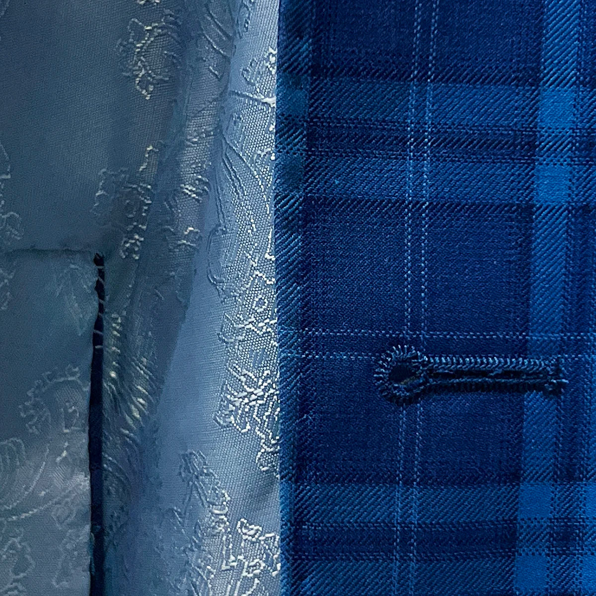 buttonholes adding a stylish touch to a colbalt blue checkered plaid men's sport coat.
