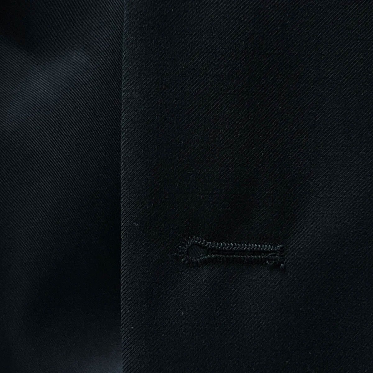 buttonholes adding a unique touch to a classic black men's suit.