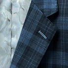 Detail of contrast buttonholes on a Prussian Blue men's sportcoat with black grid checks.