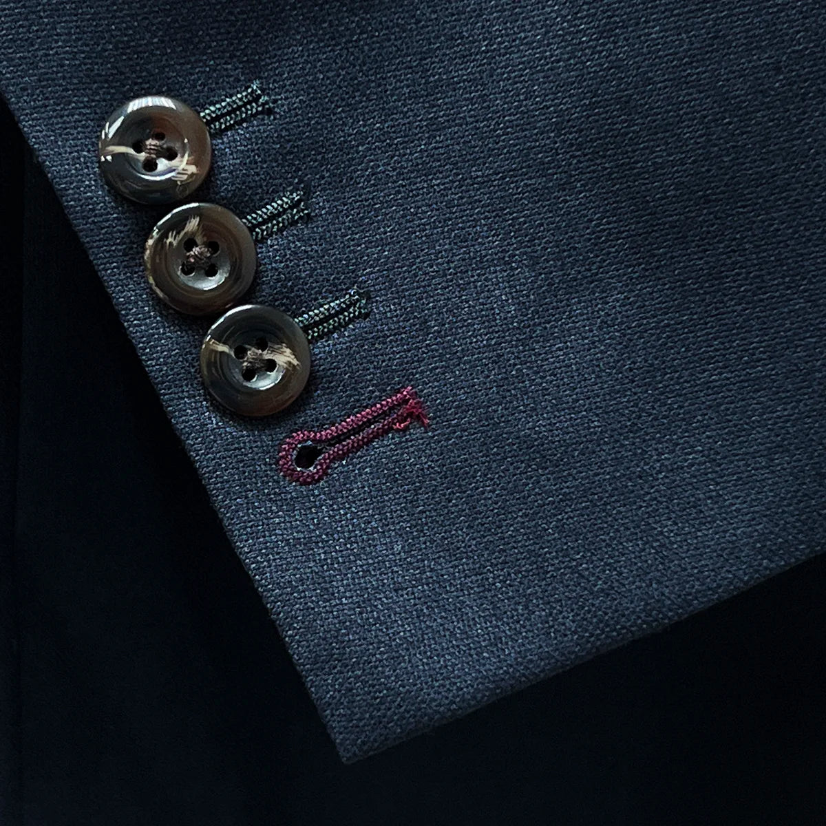 Detail of contrast buttonholes on a grey suit