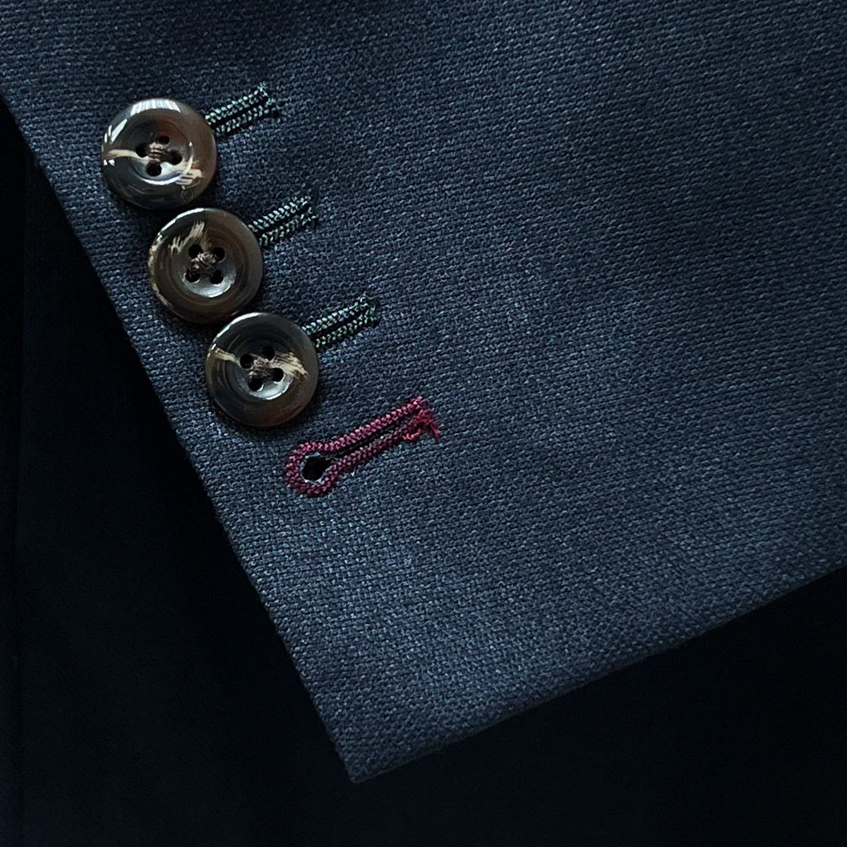 Detail of contrast buttonholes on a grey suit