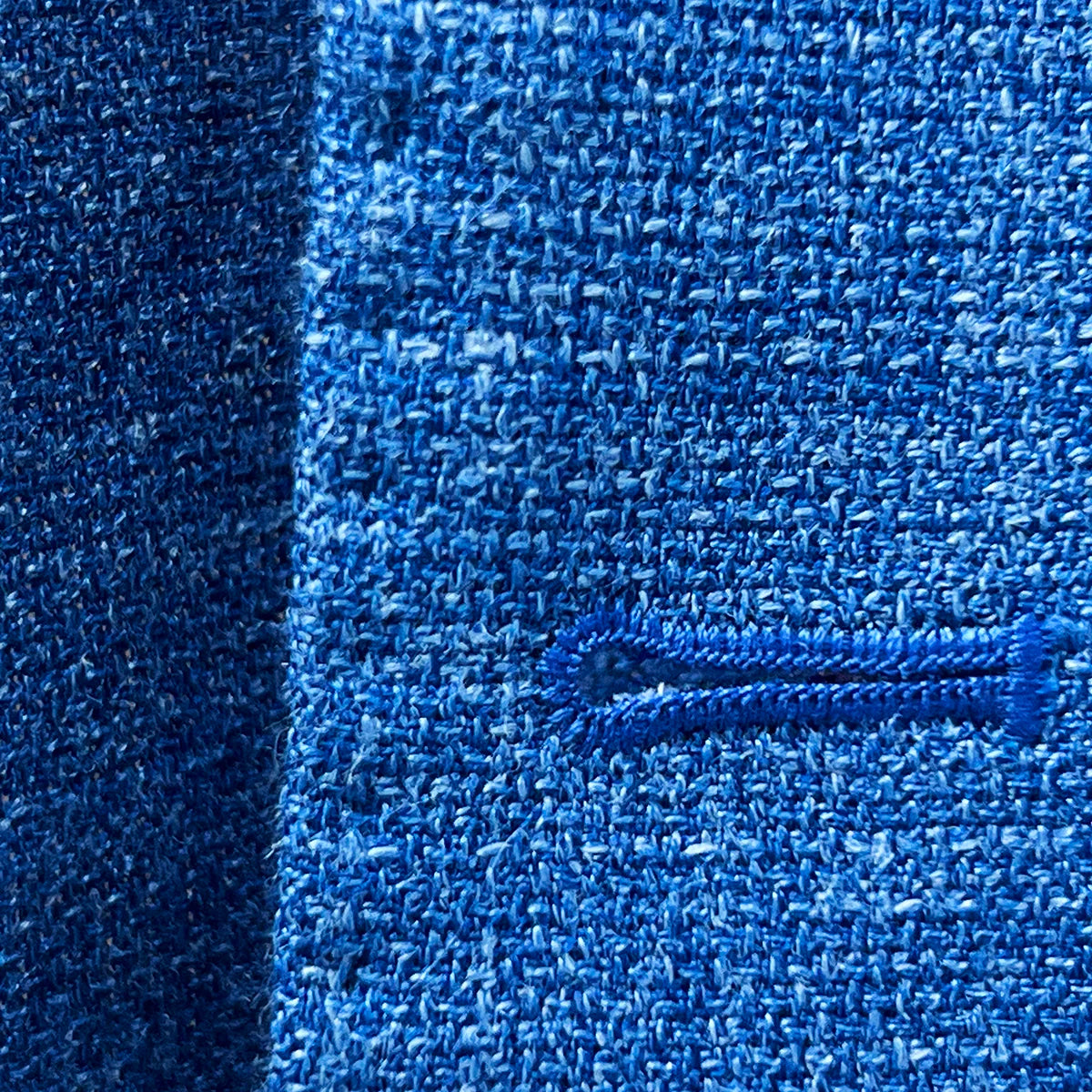 Close-up of the buttonhole stitching on the sportcoat, showing the precise matching pick stitching and fabric texture.