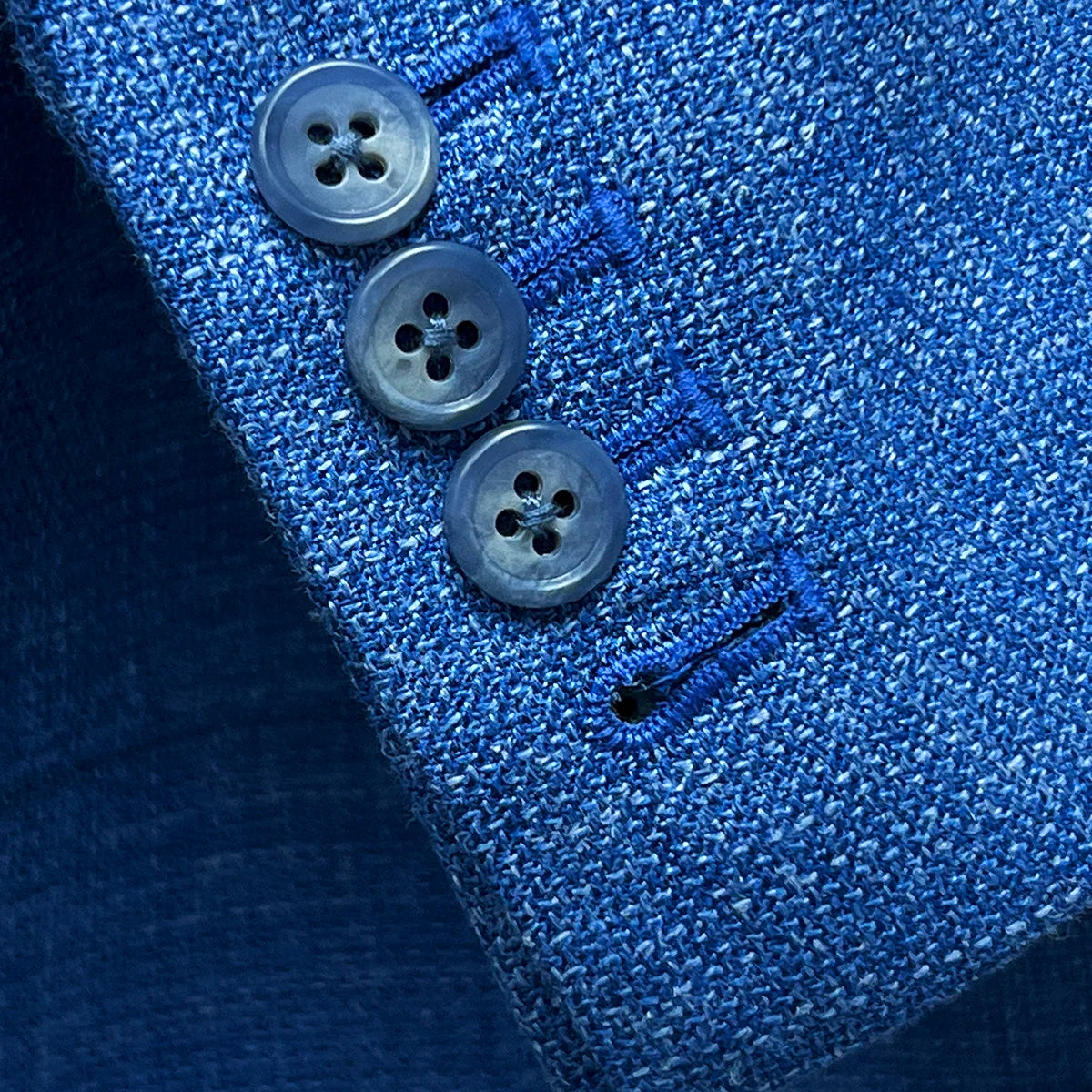 Functional sleeve buttonholes on the sportcoat, featuring matching pick stitching and blue horn buttons.