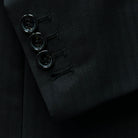 Functional sleeve buttonholes on a black herringbone suit.