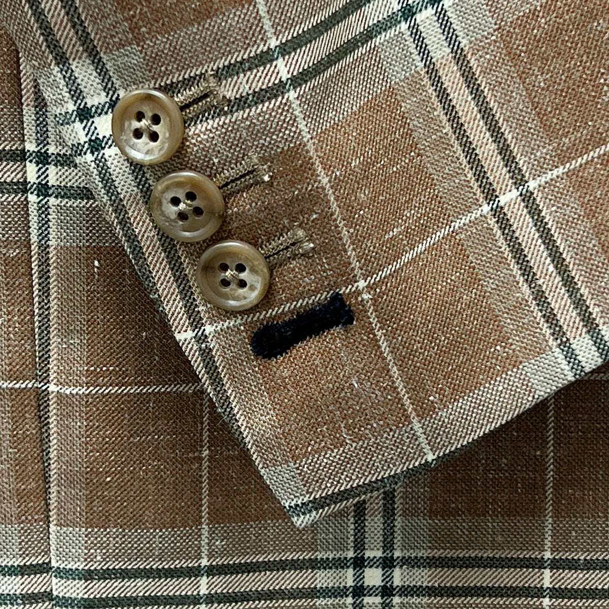 Functional sleeve buttonholes on a brown beige men's sport coat with blanched almond and midnight blue windowpane pattern.