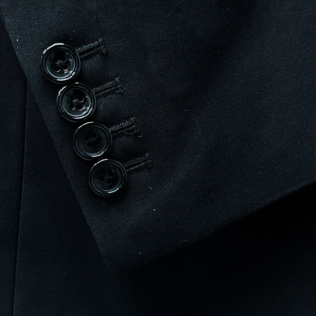 Functional sleeve buttonholes demonstrating practical design on a classic black men's suit.