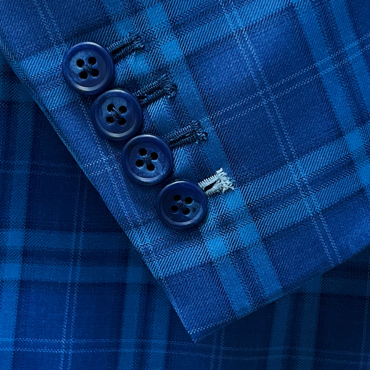 Functional sleeve buttonholes adding a practical feature to a colbalt blue checkered plaid men's sport coat.