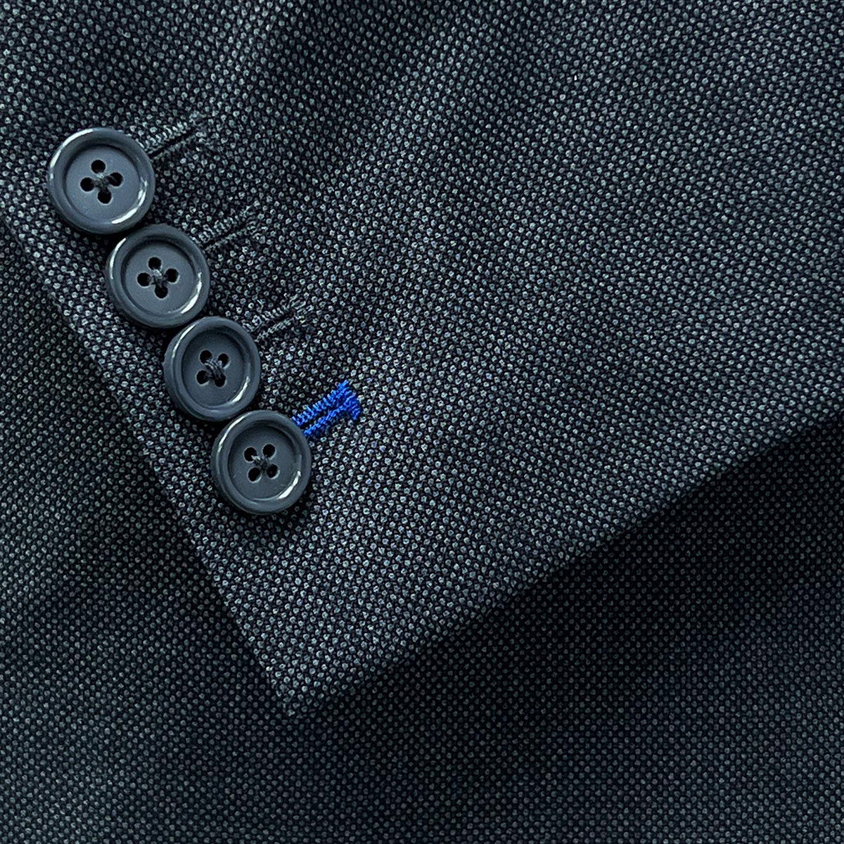 Functional sleeve buttonholes offering both style and utility on a dark grey birdseye suit.