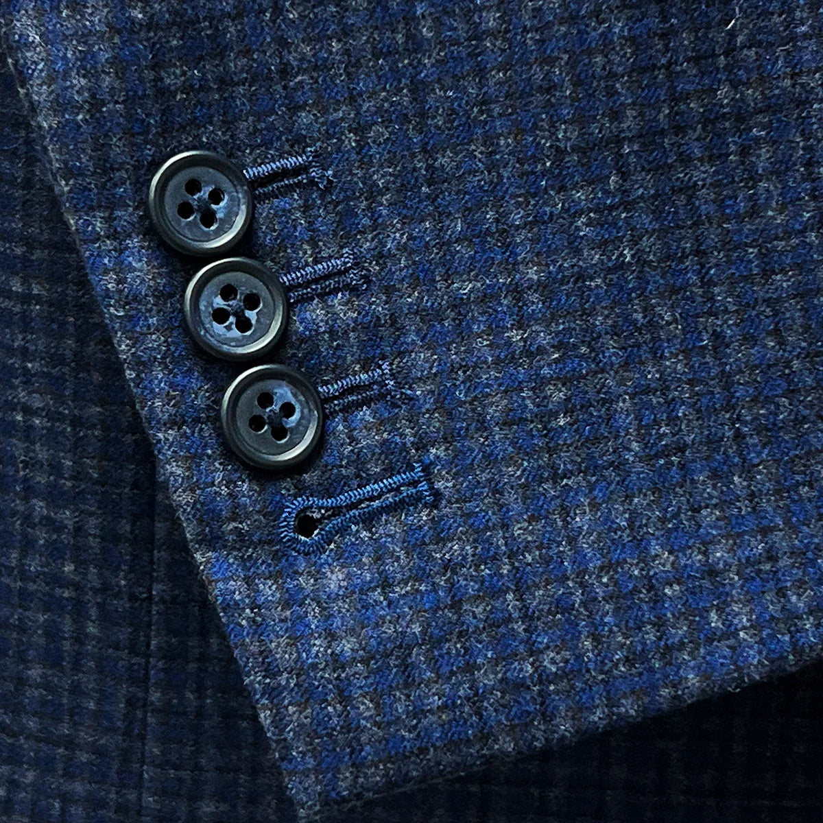 Functional sleeve buttonholes on a gray blue mini grid checks sport coat made of flannel wool for practical style.