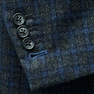 Functional sleeve buttonholes on a grey blue grid check sportcoat.