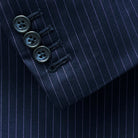 Functional sleeve buttonholes on a navy suit with purple pinstripes, blending form with function.