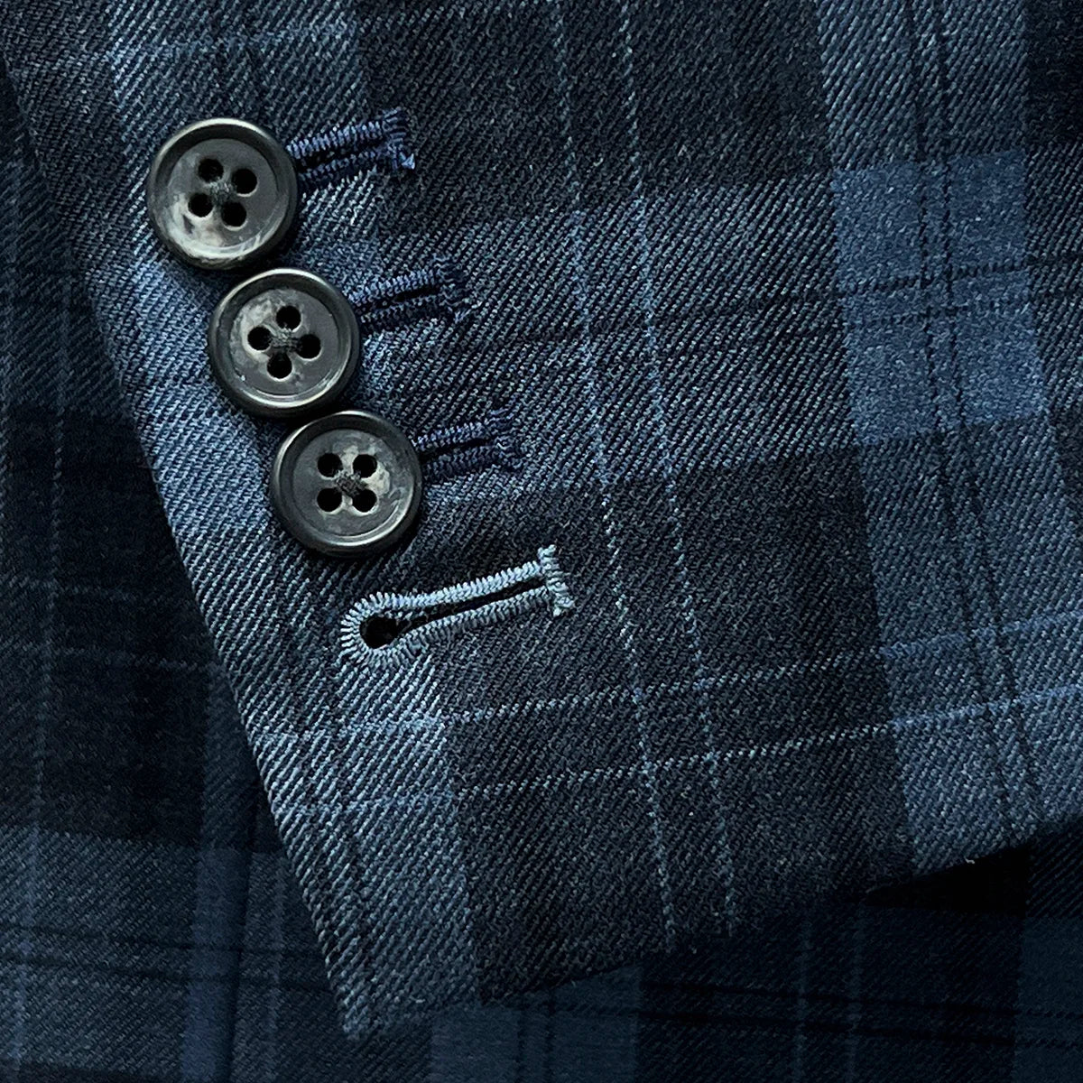 Functional sleeve buttonholes on a Prussian Blue sportcoat with black grid checks.