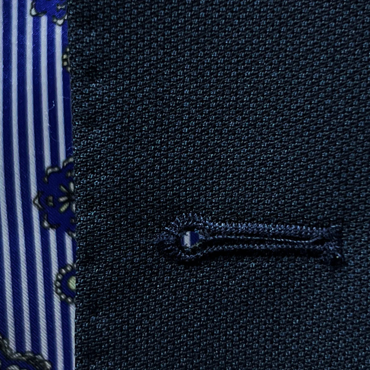 Macro shot of handcrafted buttonhole stitching showing precise black contrast thread work