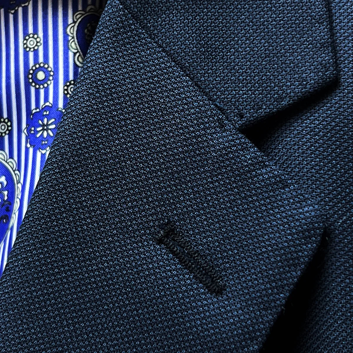 Close-up of notch lapel showing pick stitching detail and black accent buttonhole