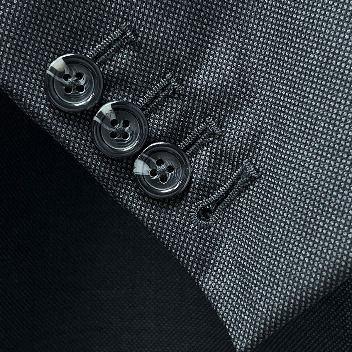 Close-up of working sleeve buttonholes with dark grey horn buttons on Super 150's wool fabric